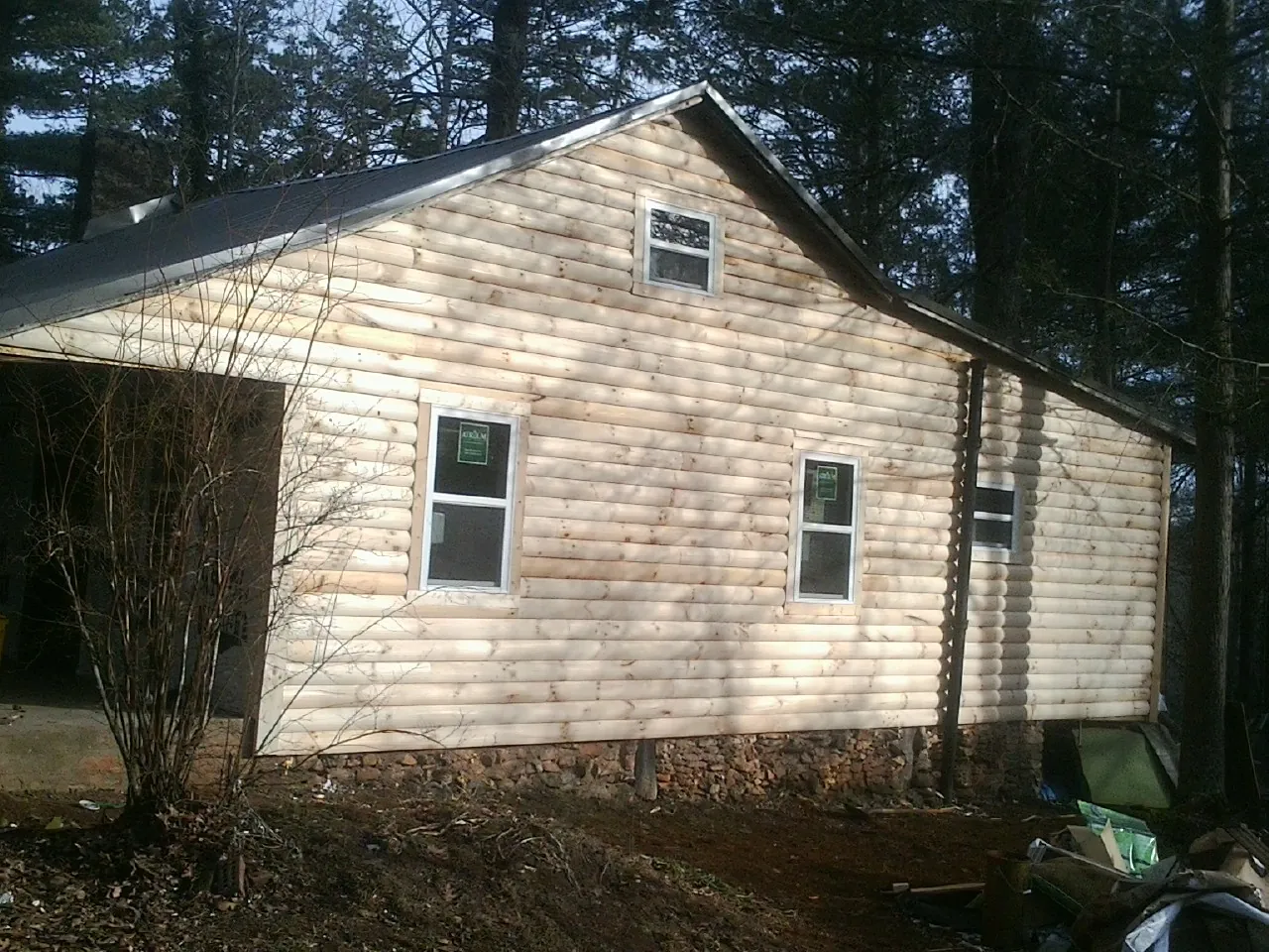 New log siding and dark metal roofing on a gable end in Gretna